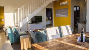 A modern living room with a staircase, a dining area, and a kitchen. - Desert Sands Boutique B&B - Self-Catering (Swakopmund)