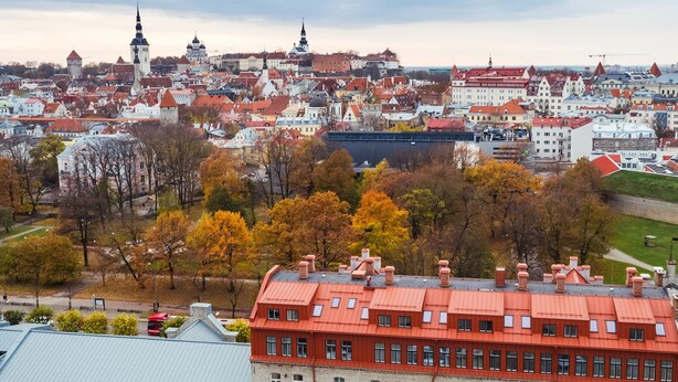 A historic building with a red roof and stone facade, surrounded by a parking lot and trees with autumn foliage. - Lighthouse Apartments Tallinn (Tallinn)