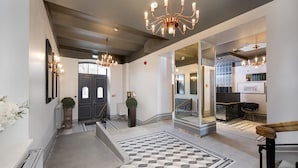 A modern hotel lobby with a geometric patterned floor, a grand chandelier, and a staircase leading to the upper floors. - Lighthouse Apartments Tallinn (Tallinn)