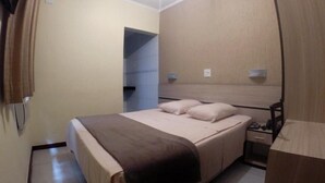 A hotel room with a bed, bedside table, and a mirror. - Hotel Brigadeiro (São Paulo)