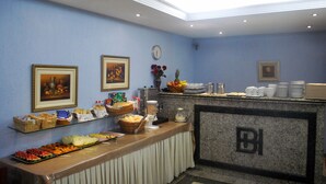 A buffet area with various food items, a clock, and framed artwork on the wall. - Hotel Brigadeiro (São Paulo)