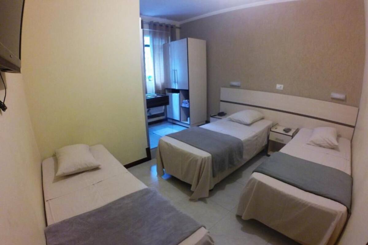 A hotel room with two single beds, a desk, and a wardrobe.