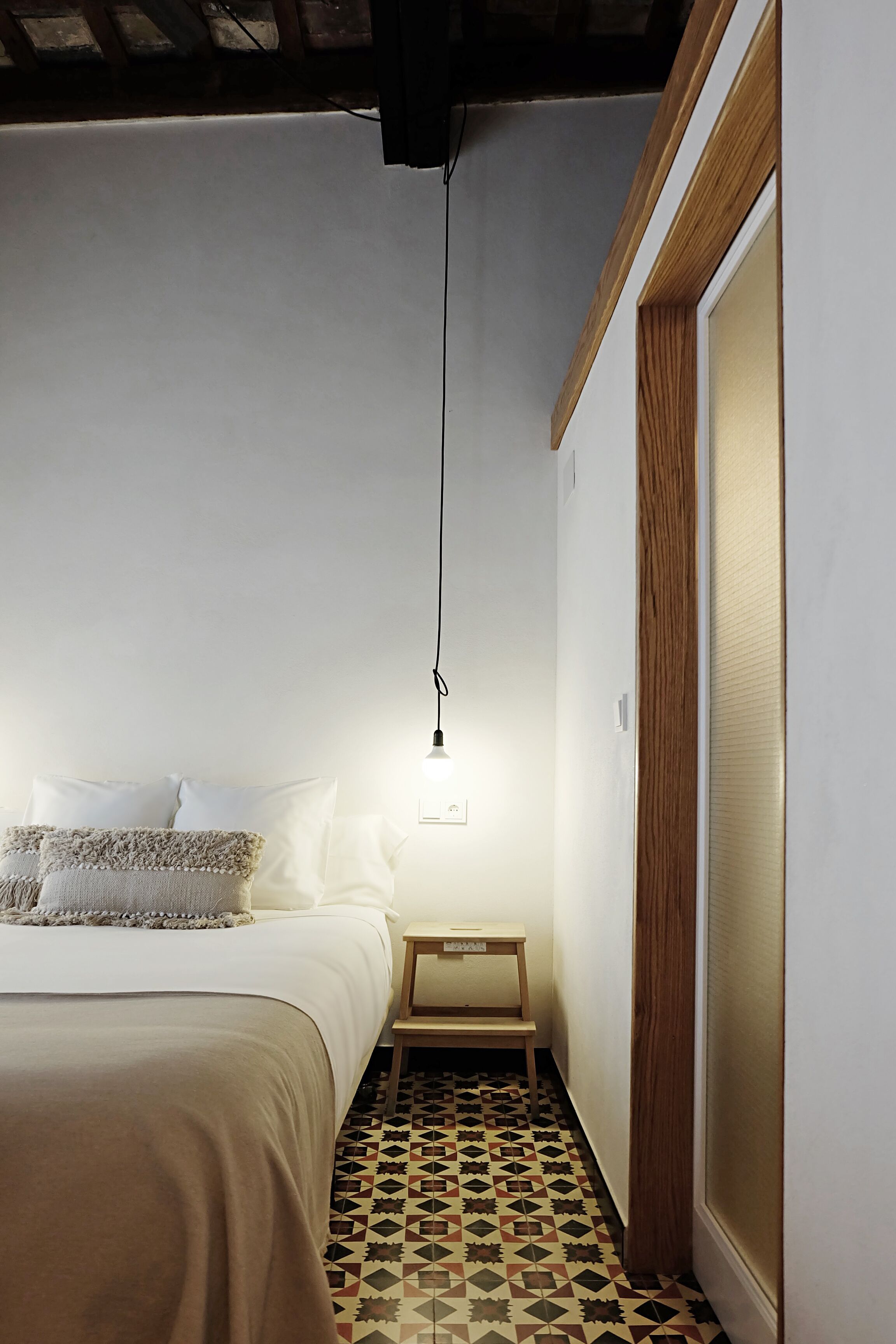 Un dormitorio con una cama, una mesita de noche y una lámpara colgante.