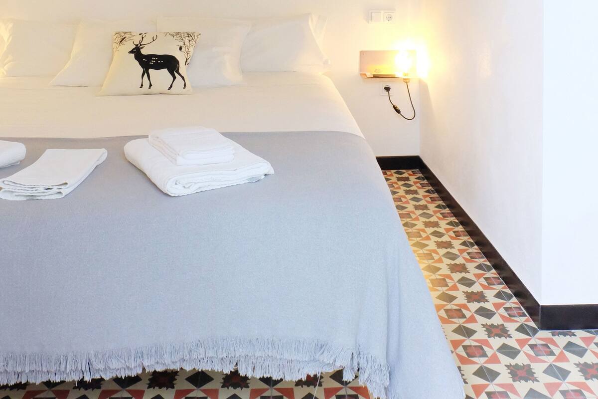 A bedroom with a bed, a nightstand, a lamp, and a patterned floor.