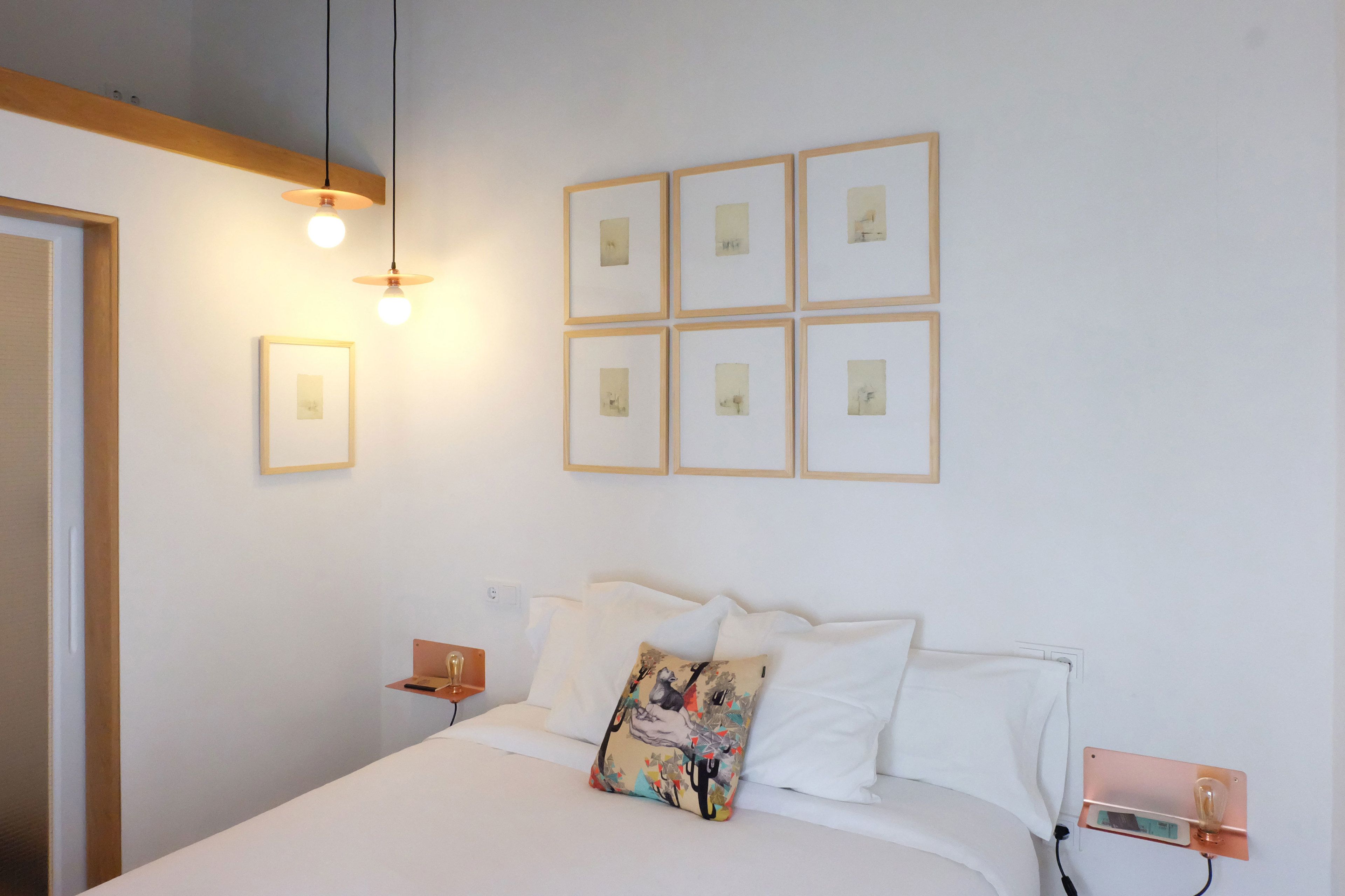 A neatly arranged bedroom with a bed, bedside tables, and wall-mounted lights.