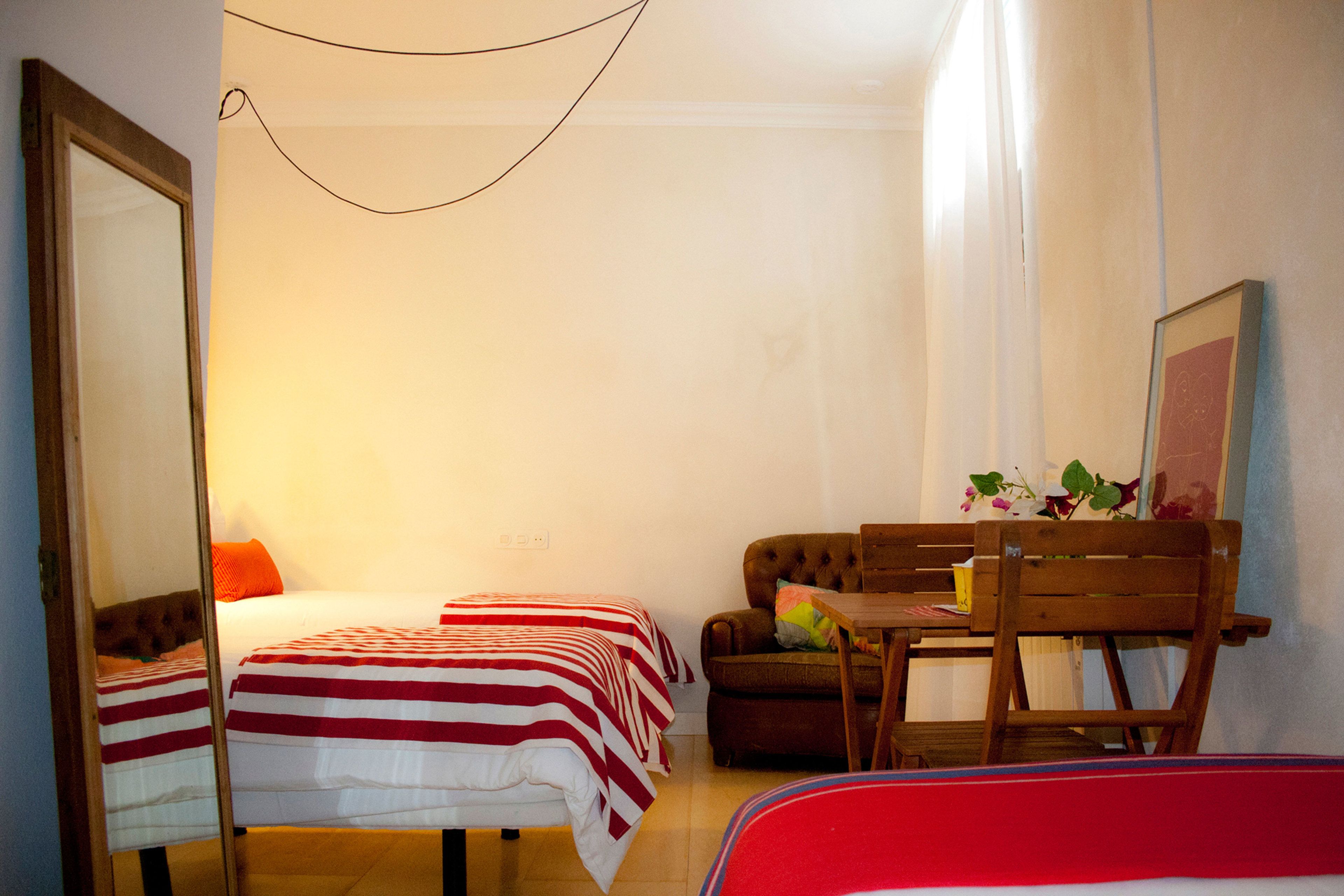Una habitación pequeña y luminosa con cama, sofá, mesa y silla.