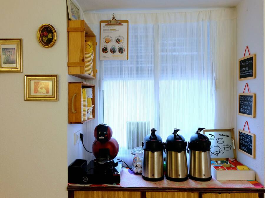 Un plan de travail de cuisine avec une machine à café, deux bouilloires électriques et un bocal rempli d’œufs.