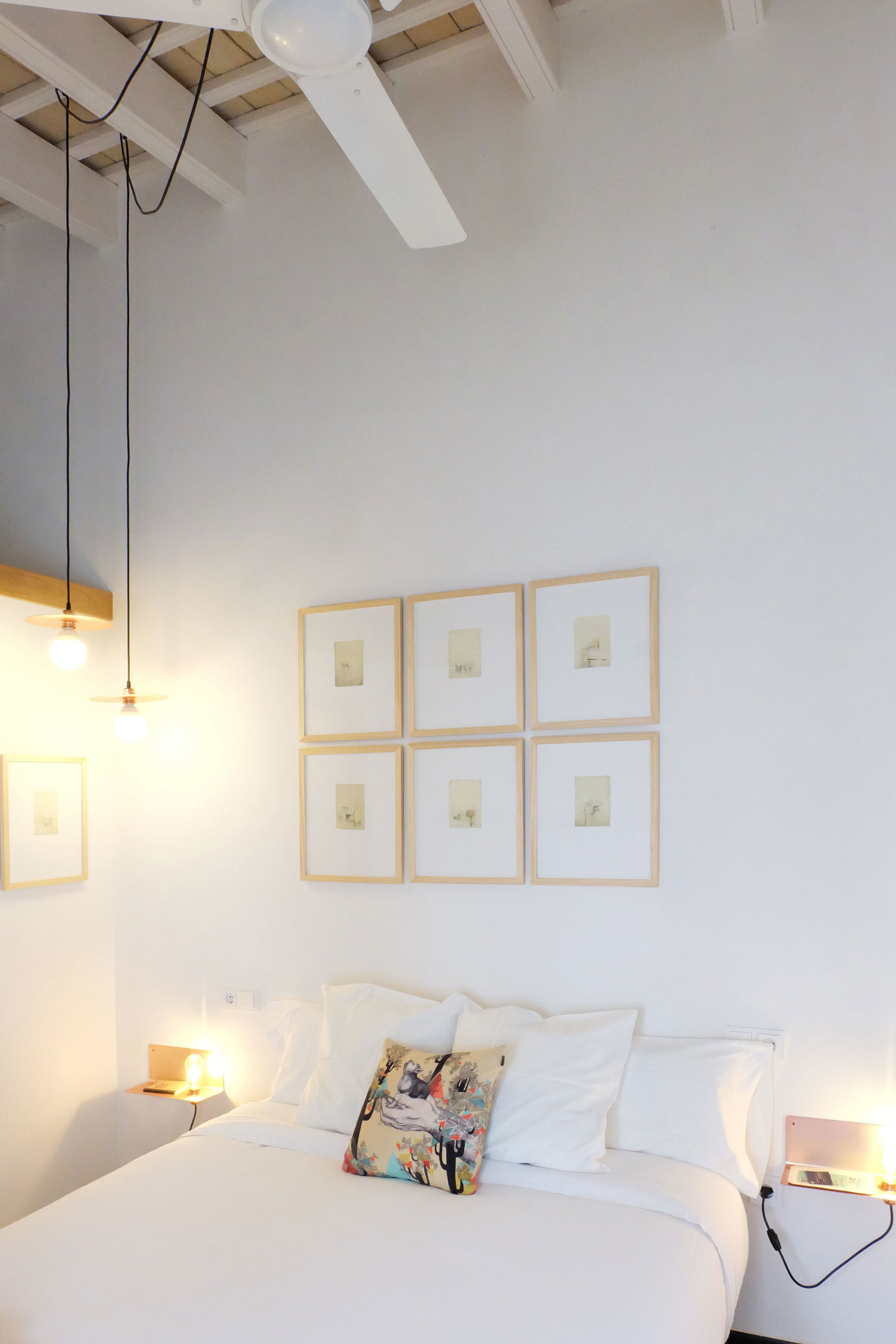 A bedroom with a bed, bedside lamps, and framed pictures on the wall.