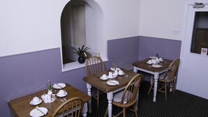 A dining area with tables set for four, each with white tableware and a vase of flowers. - Fourways Guest House (Thirsk)