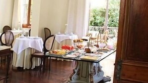 Een eetruimte met gedekte tafels, stoelen en uitzicht door een raam.
