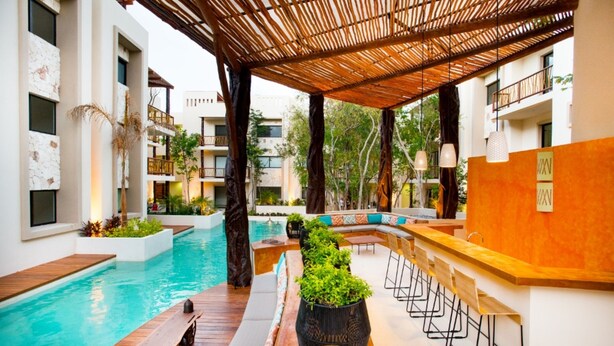Ein Poolbereich mit Holzterrasse, Sitzgelegenheiten und einer Bar.