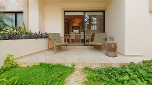 Ein Terrassenbereich mit zwei Stühlen, einem kleinen Tisch und einem dekorativen Holzstumpf.