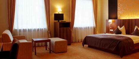 Une chambre d’hôtel avec un lit, un canapé, une table et un téléviseur.