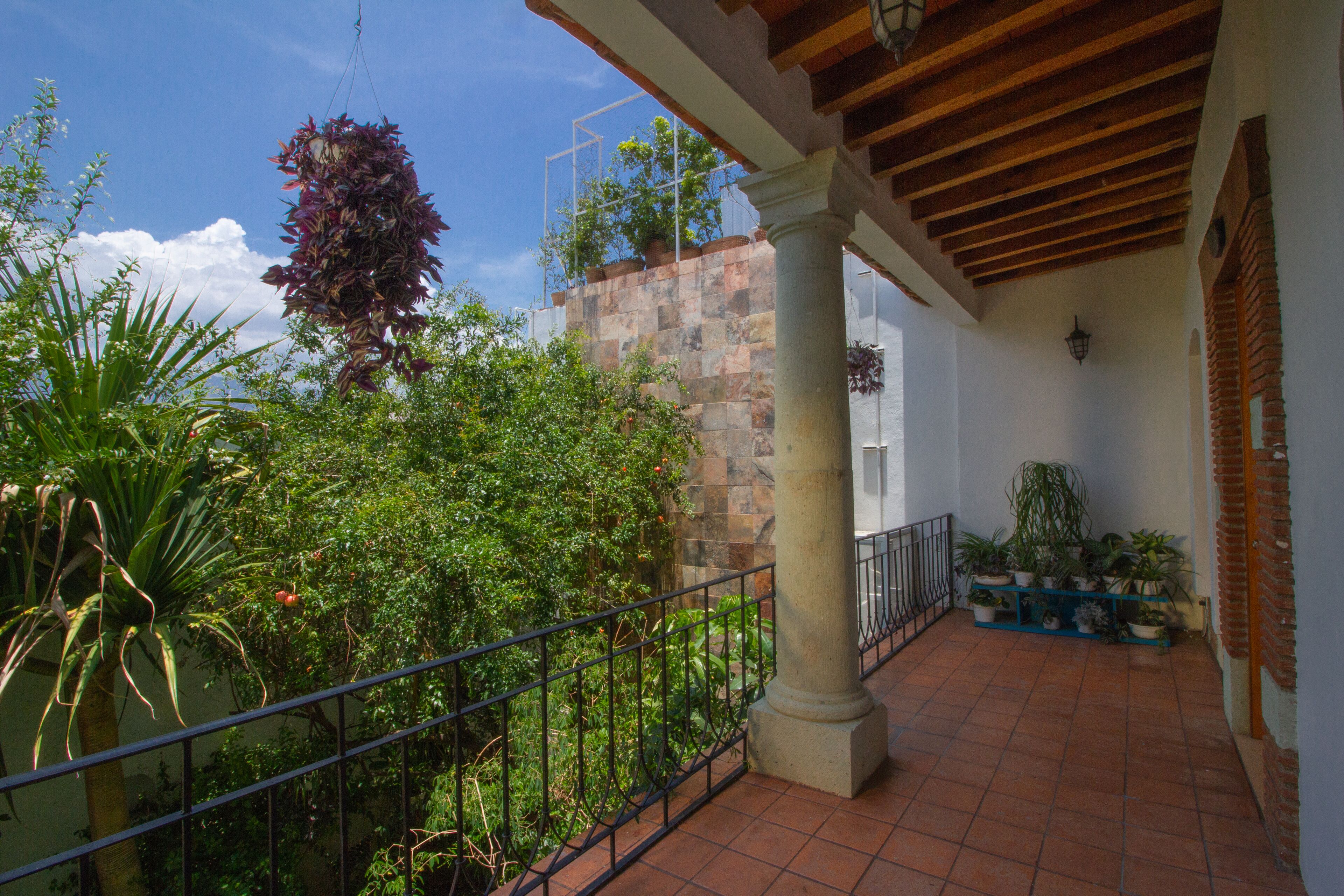 A covered outdoor area with a stone wall, potted plants, and a metal railing.