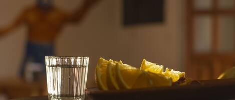 A glass of water and a plate with sliced fruit on a table.