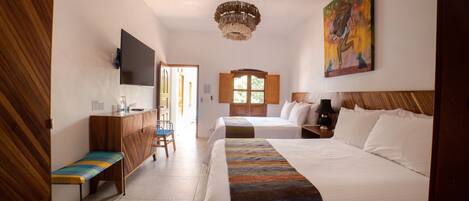 A hotel room with two beds, a wooden bench, a desk, a television, and a painting on the wall.
