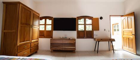 A bedroom with two beds, wooden furniture, a flat-screen TV, and a window.
