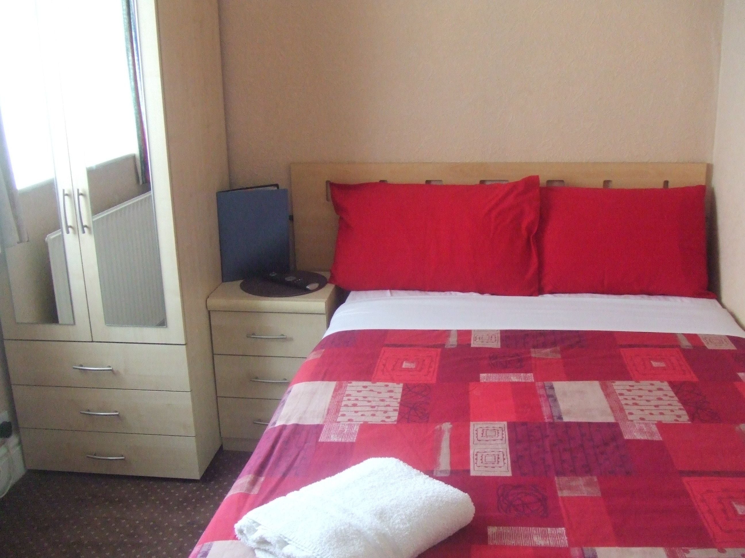 A bedroom with a bed, a dresser, a mirror, and a nightstand.