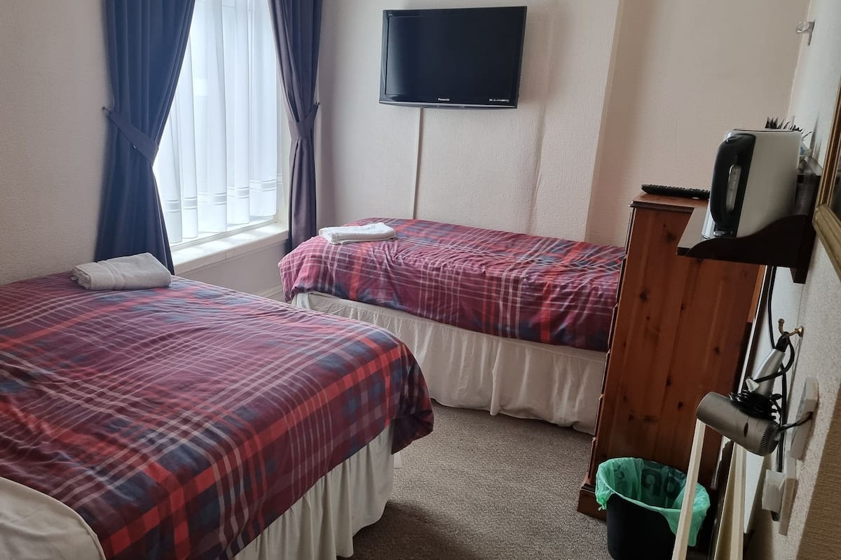 A hotel room with two beds, a TV on the wall, and a hairdryer on the wall.