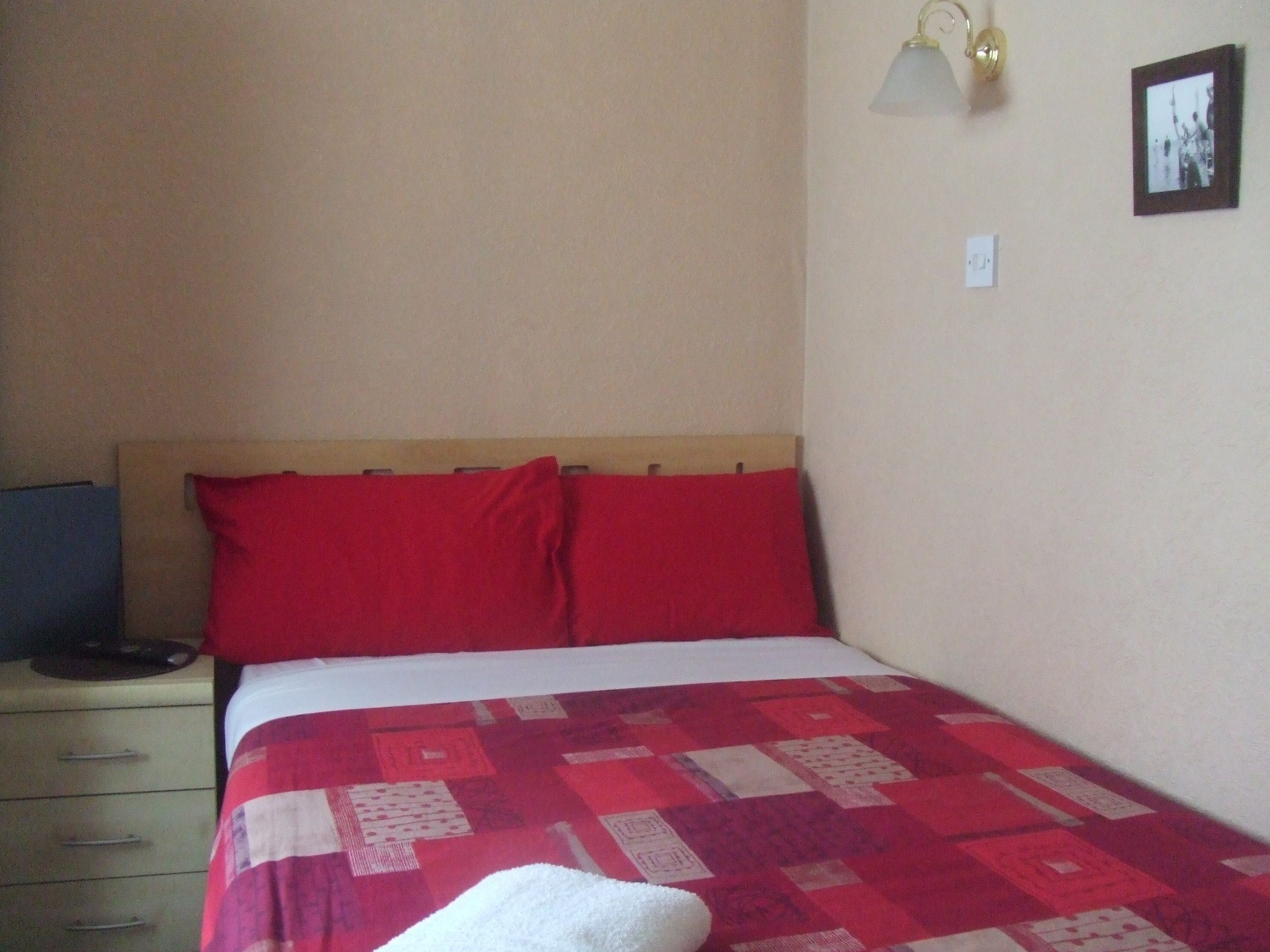 A bedroom with a bed, a nightstand, a lamp, and a framed picture on the wall.