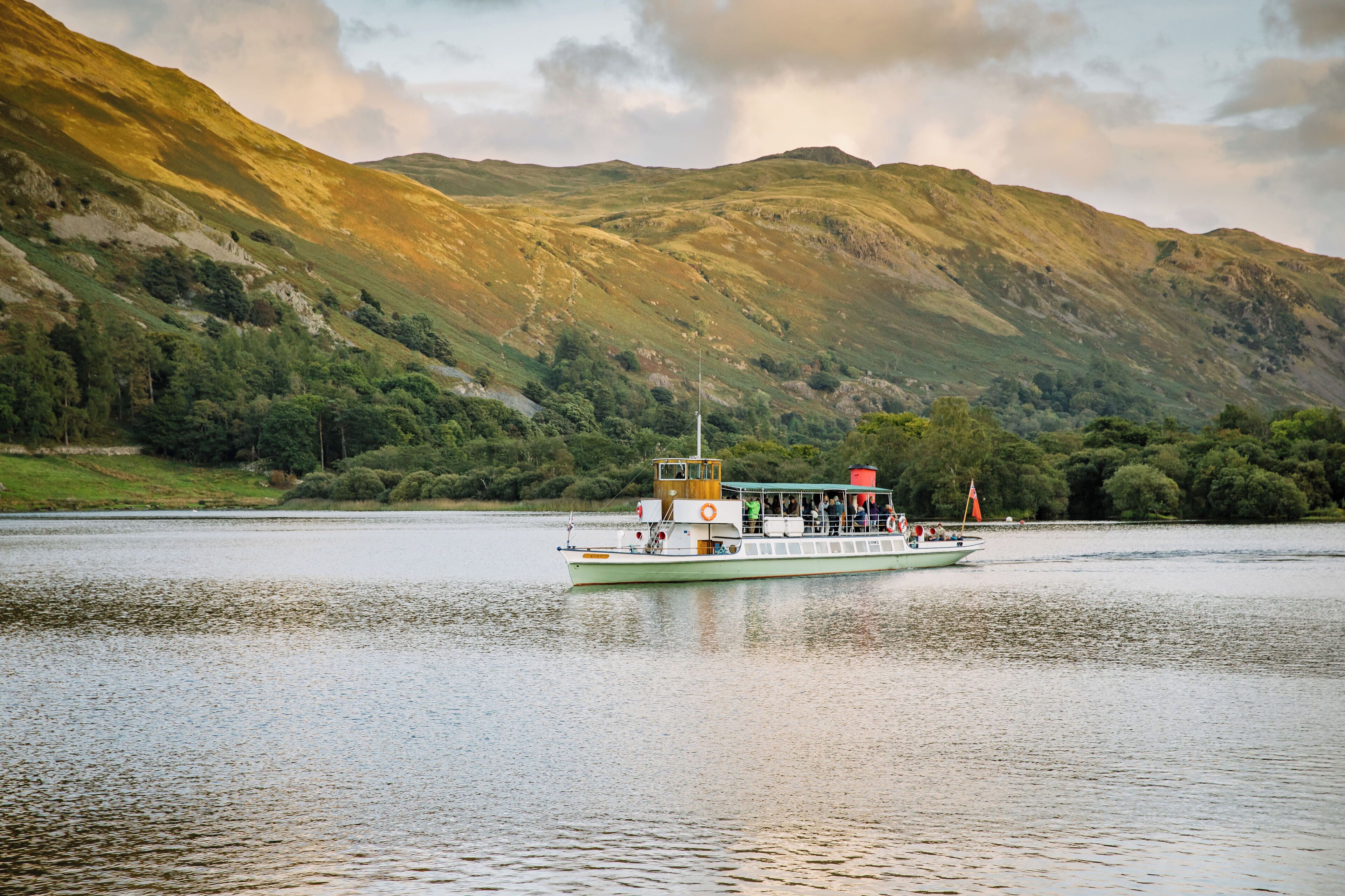 A boat on a calm river with a mountainous backdrop.