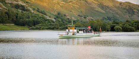 A boat on a calm river with a mountainous backdrop.