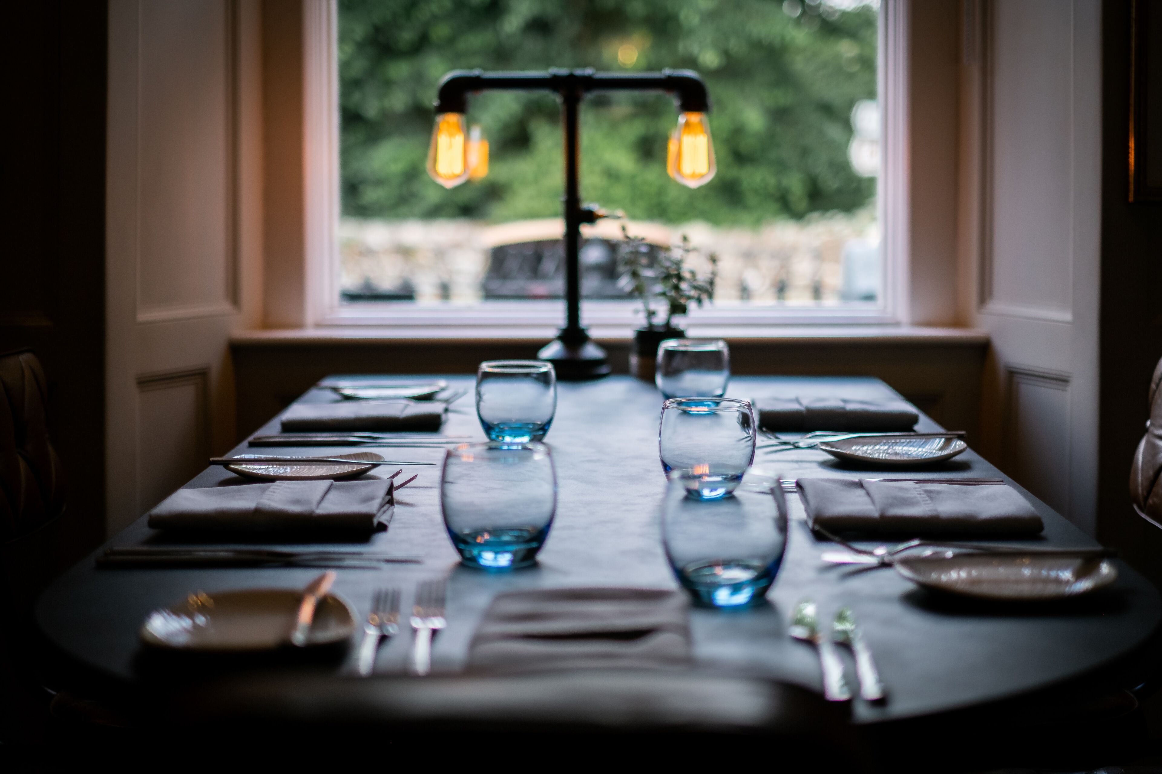 A dining table set for four with a view of greenery outside.