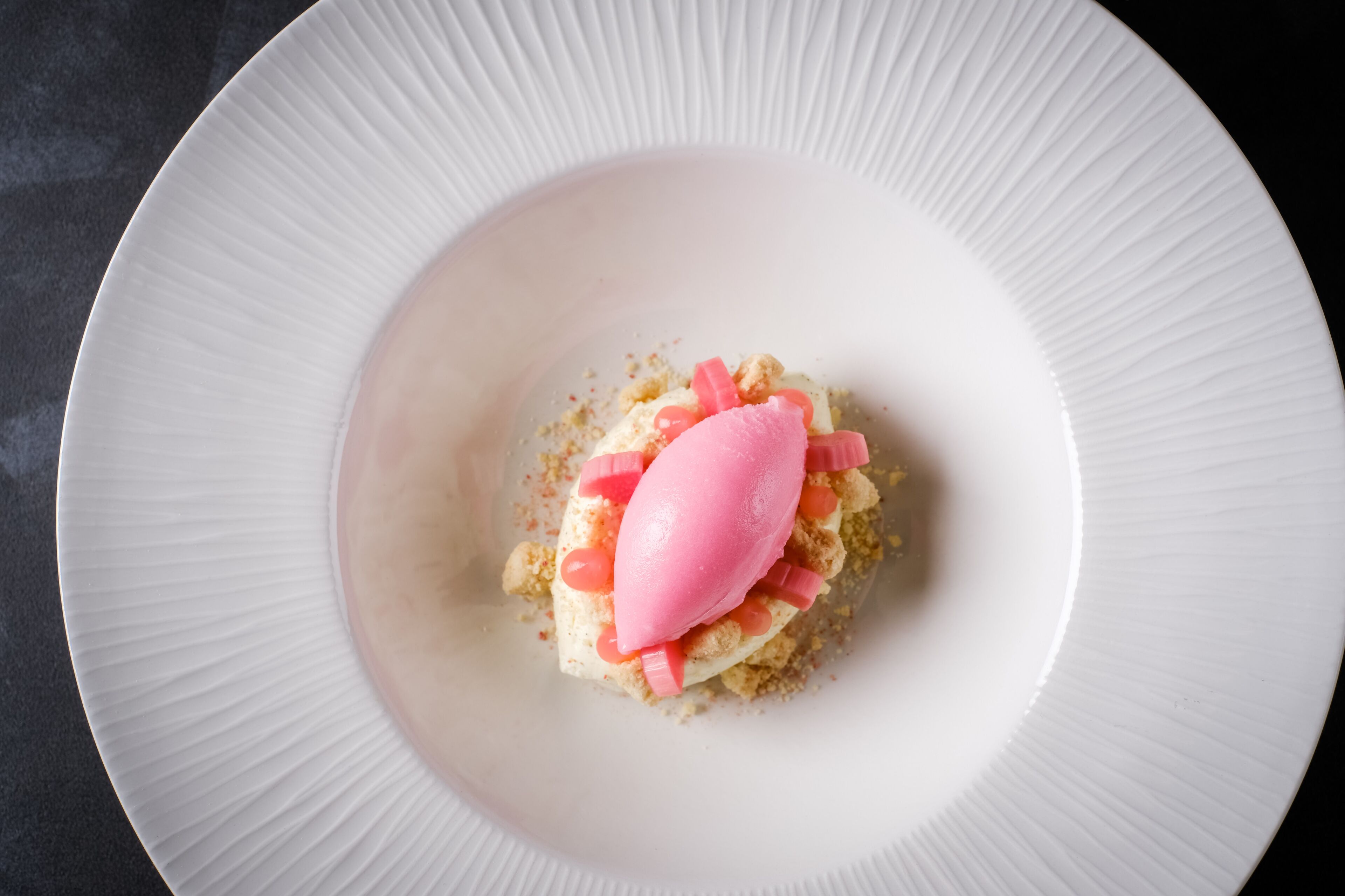 A dessert on a white plate with a textured rim.