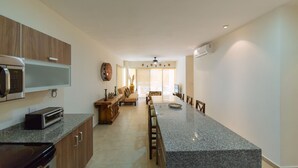 A modern kitchen with granite countertops, wooden cabinets, a built-in oven, and a microwave. - Private pool Access 2BR condo in the best location in Tulum (Tulum)