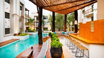 A poolside area with a wooden deck, seating, and a bar.
