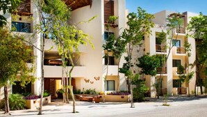 A modern hotel with multiple floors, balconies, and a courtyard with trees. - Private pool Access 2BR condo in the best location in Tulum (Tulum)