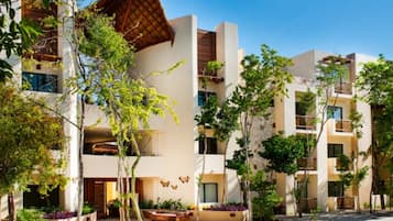 A modern hotel with multiple floors, balconies, and a courtyard with trees.