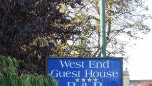Placa para a West End Guest House, indicando que é um B&B com estacionamento privativo e banheiro interno.