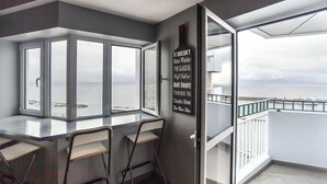 A modern room with a large window, a glass partition, and a view of the sea. There are two chairs and a table. - Atlantic Home Azores (Ponta Delgada)