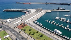 An aerial view of a marina with boats docked, a curved road, and a bridge. - Atlantic Home Azores (Ponta Delgada)