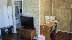 A small, furnished room with a wooden desk, a television, a telephone, and a microwave. - Virden Motel (Virden)