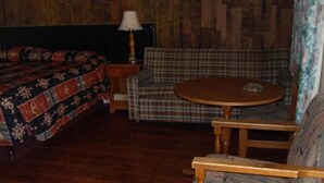 A room with a bed, a sofa, a round table, and a chair. - Virden Motel (Virden)