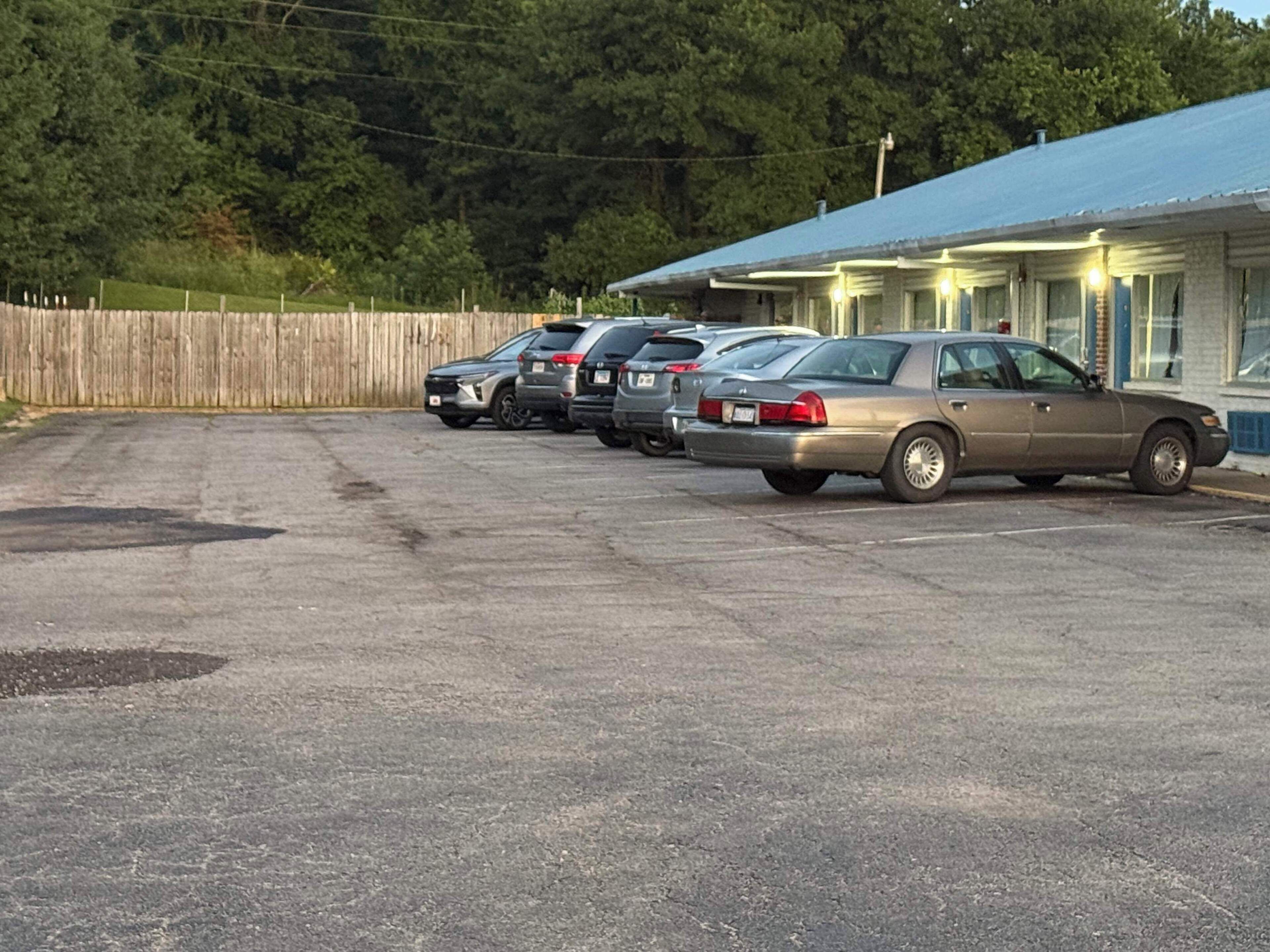 A parking lot with several cars parked in front of a building with a blue roof.