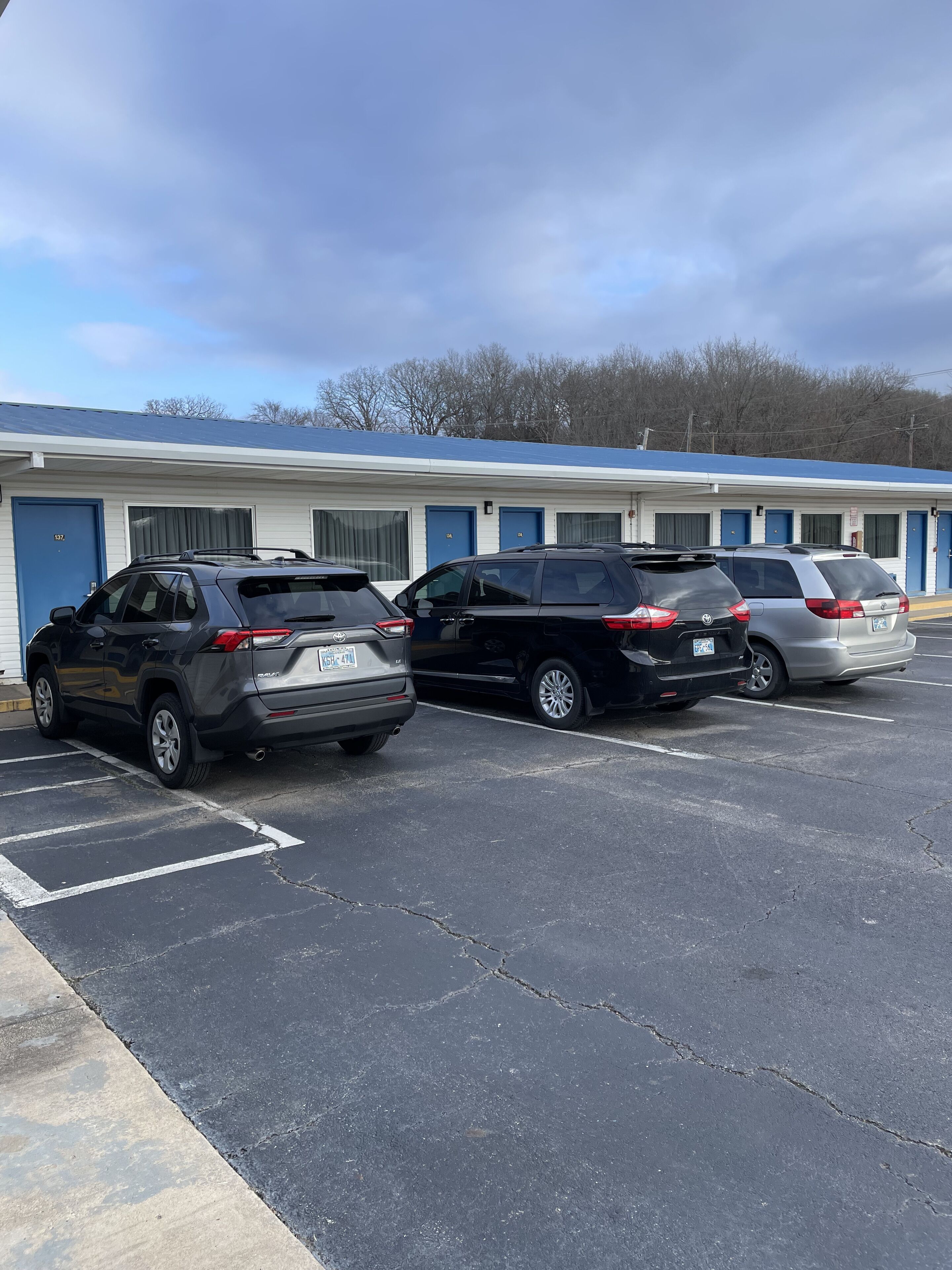 A parking lot with several SUVs parked in front of a motel with blue doors and a white exterior.