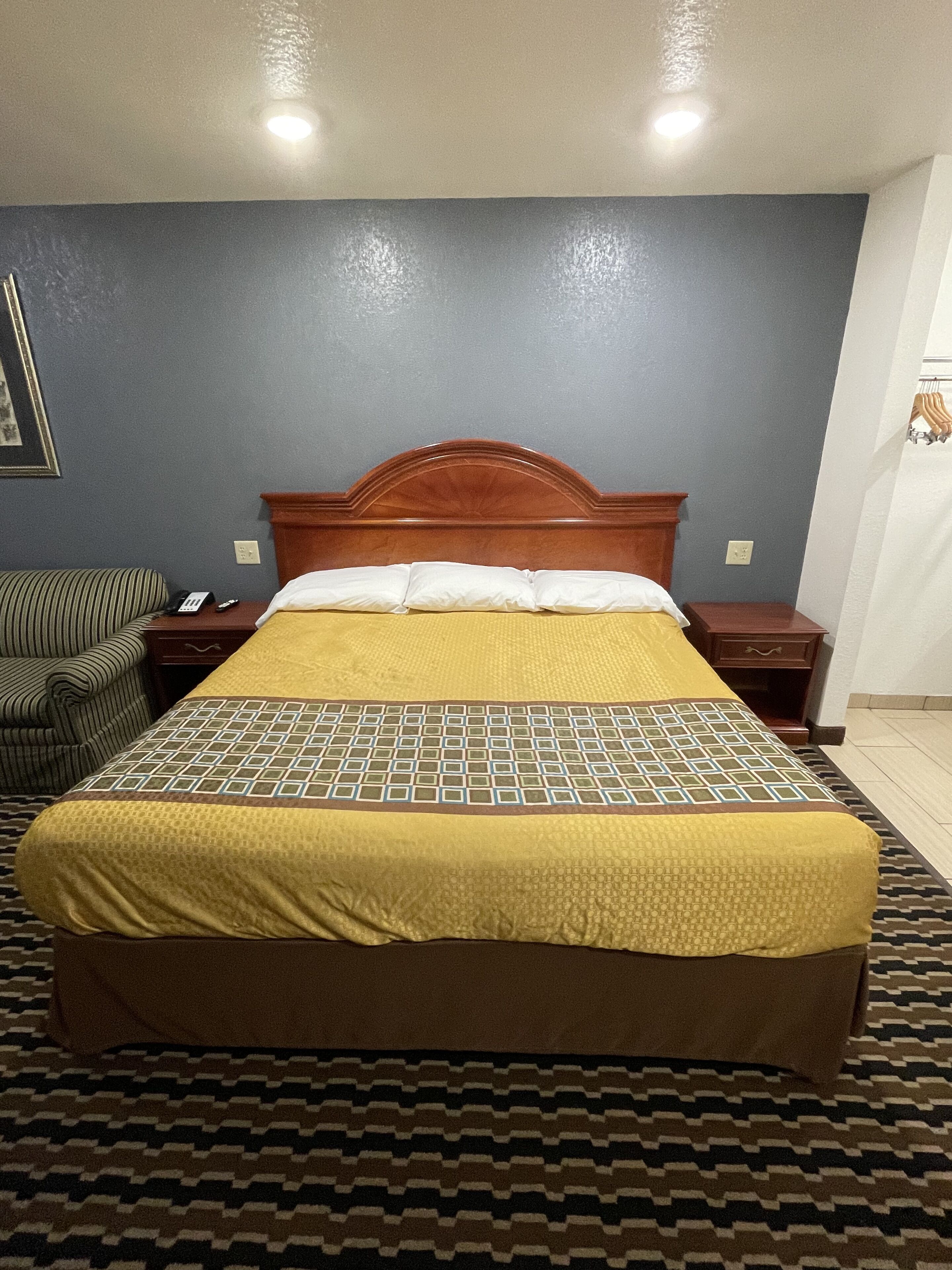 Habitación de hotel con cama, mesita de noche, silla y teléfono instalado en la pared.