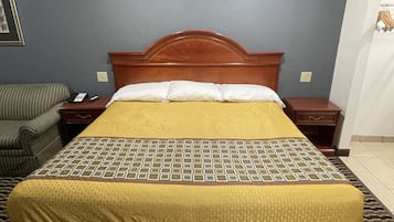 Habitación de hotel con cama, mesita de noche, silla y teléfono instalado en la pared.