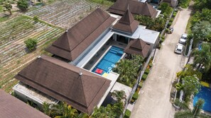 Vista aérea de una zona residencial con varias casas, una piscina y una carretera.