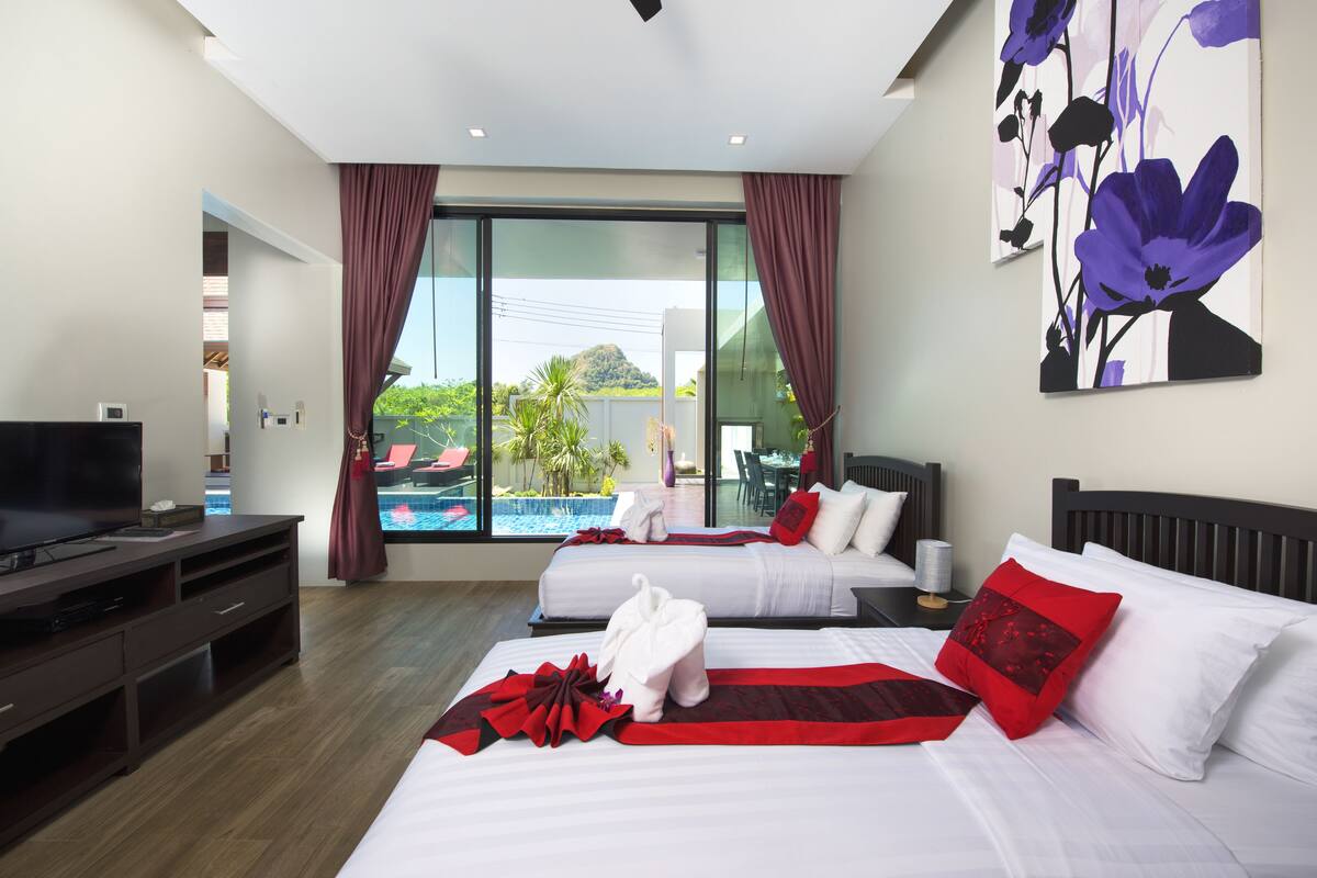 Habitación de hotel con dos camas, televisión y vistas a una piscina.