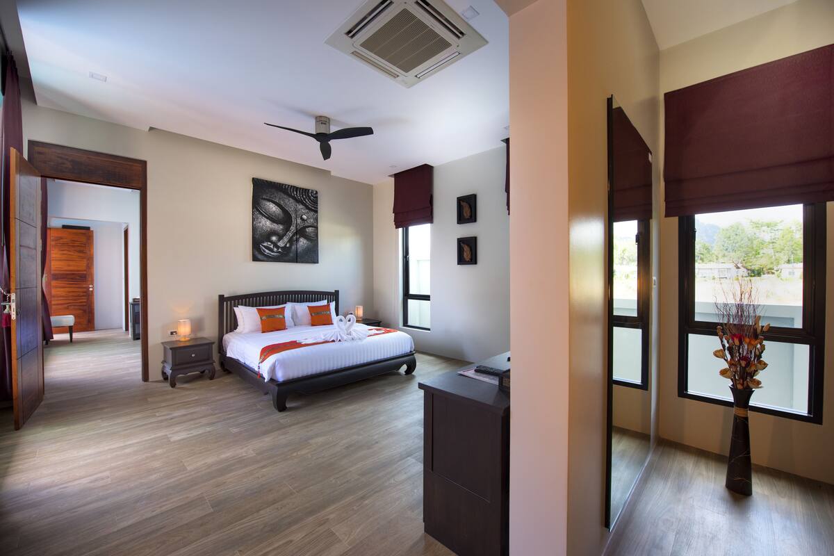 Una habitación de hotel moderna con una cama grande, un escritorio, un florero con flores y vistas al exterior.