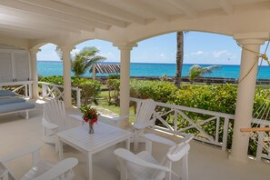 Relax in a serene ocean-view seating area with a table, chairs, and lush greenery.