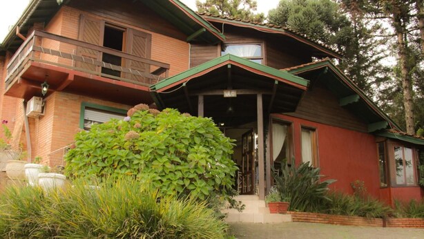 Una casa de dos pisos con balcón, porche cubierto y jardín cuidado.