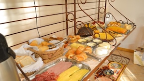 Un bufé con diversas opciones de comida, incluyendo carnes, quesos y pasteles.