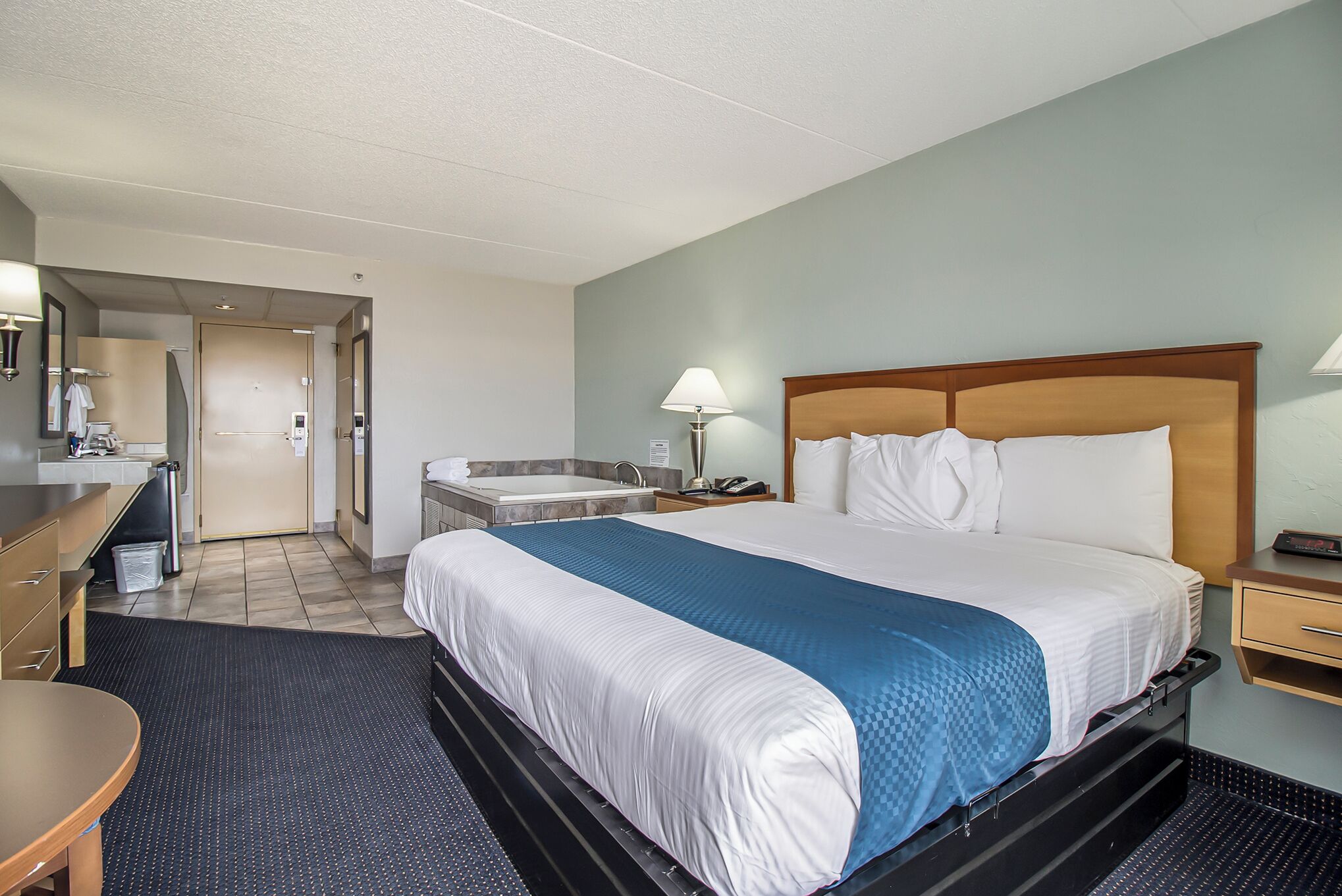 Une chambre d’hôtel équipée d’un lit, d’un bureau, d’une chaise, d’un lavabo et d’un miroir.