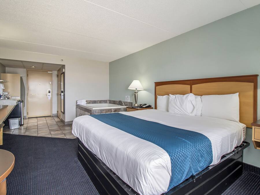 Une chambre d’hôtel équipée d’un lit, d’un bureau, d’une chaise, d’un lavabo et d’un miroir.