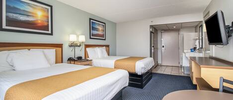 Een hotelkamer met twee bedden, een bureau, een stoel, een televisie en kunstwerken aan de wand.
